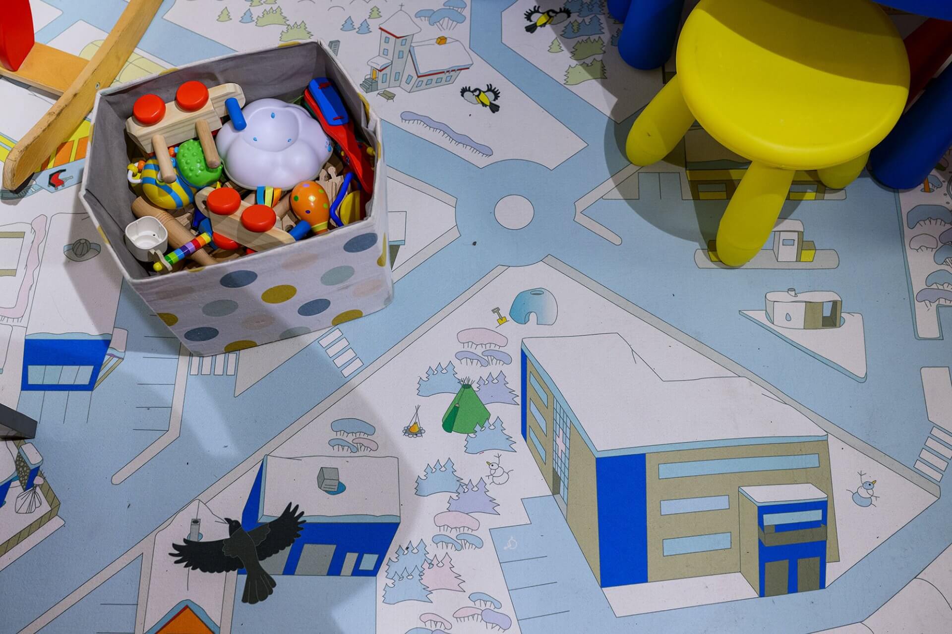 Lekematte med leker, lekekasse og gul krakk.