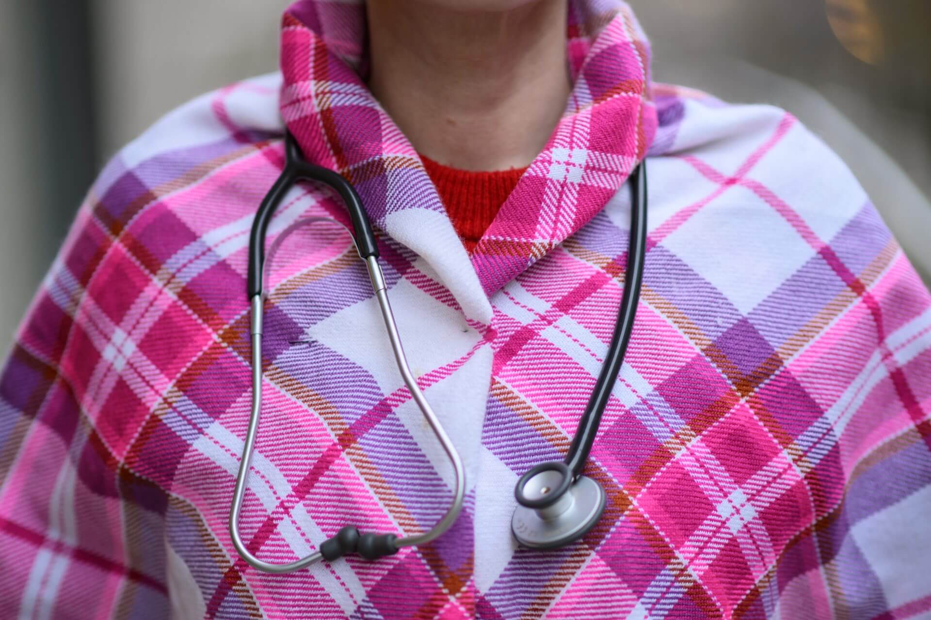Nærbilde av skulderparti med sakisk sjal i rosa farger og stetoskop.
