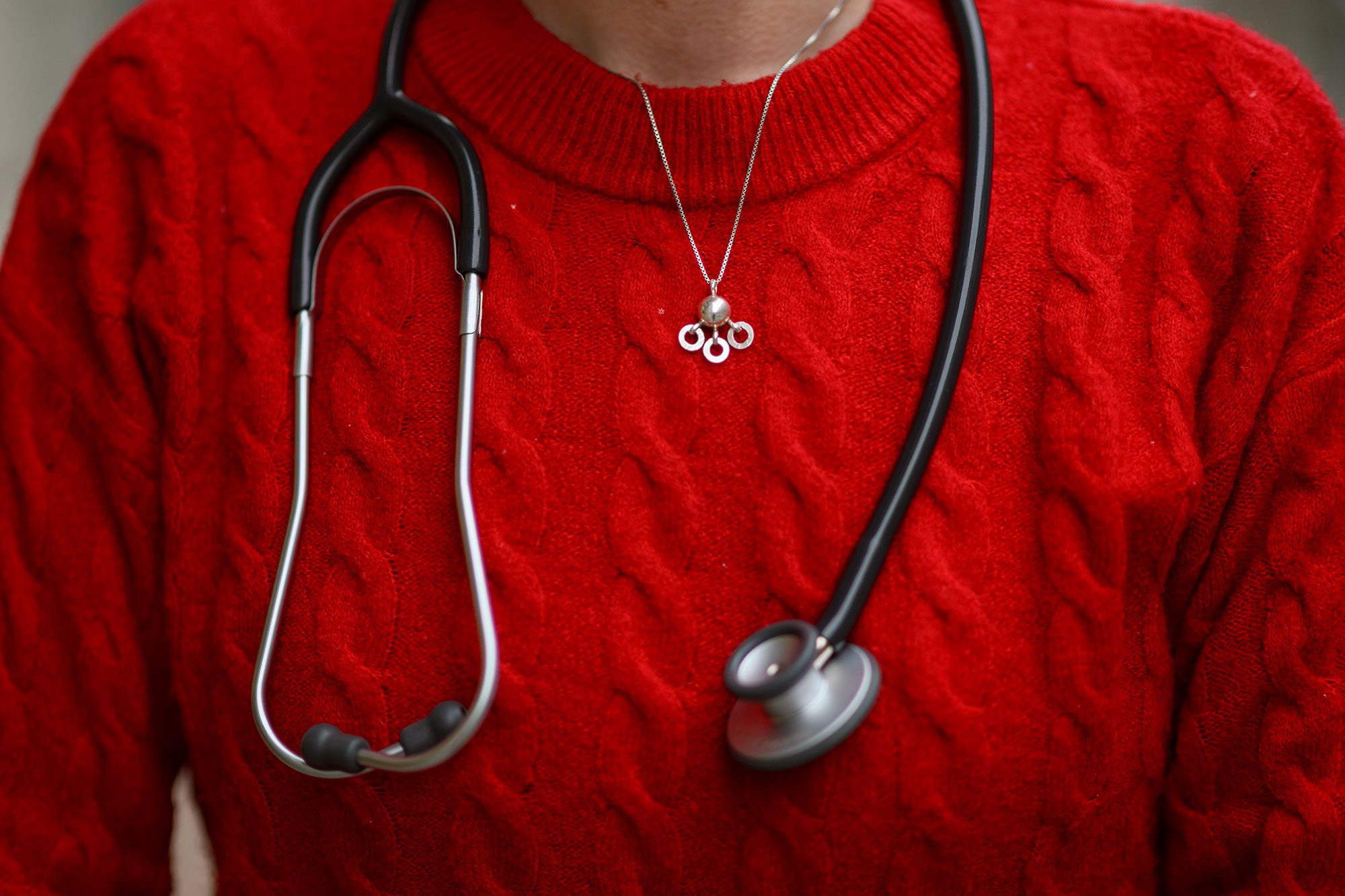 Nærbilde av kvinnelig overkropp med rød gender og stetoskop rundt halsen.
